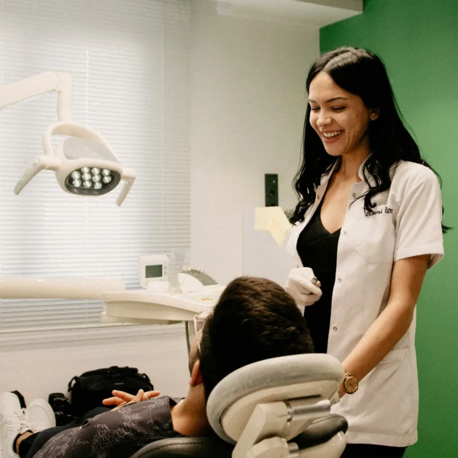 Une dentiste souriante auprès d'une personne installée dans le fauteuil