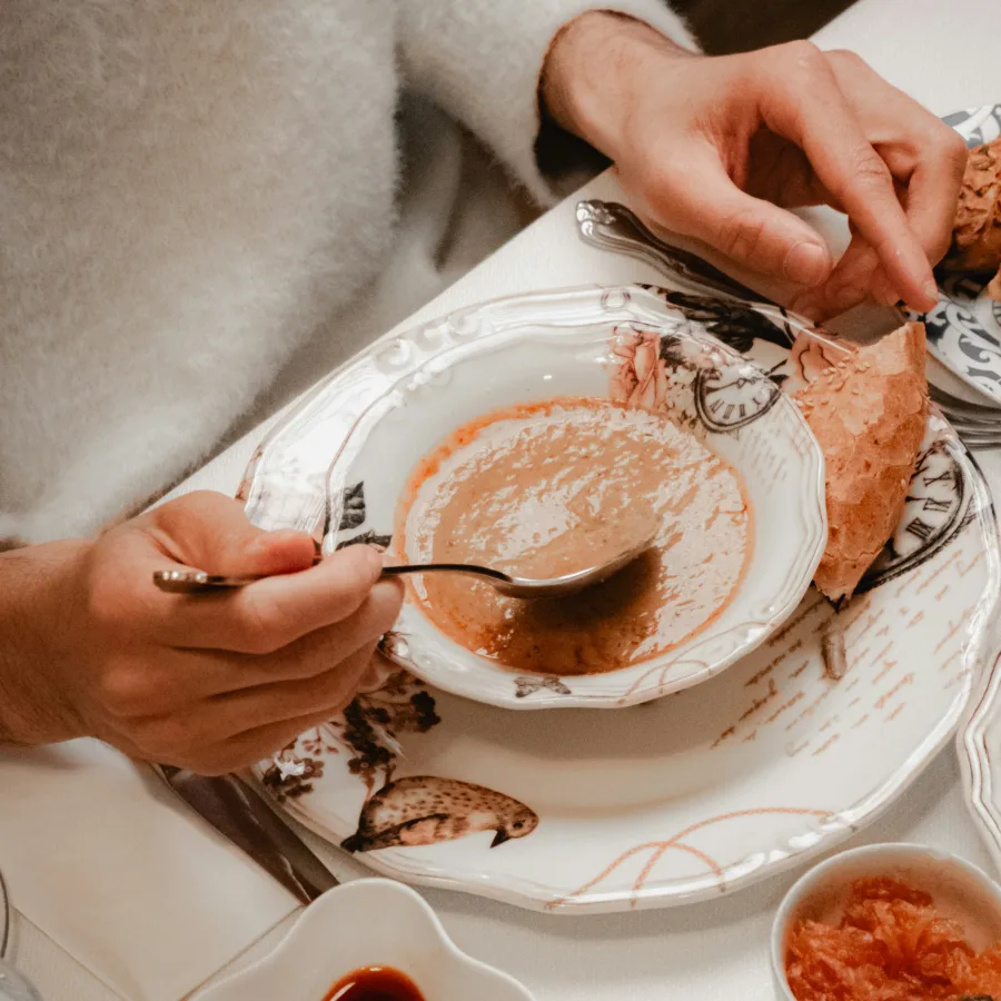 Personne à table, cuillère à la main, devant un bol de soupe presque terminé